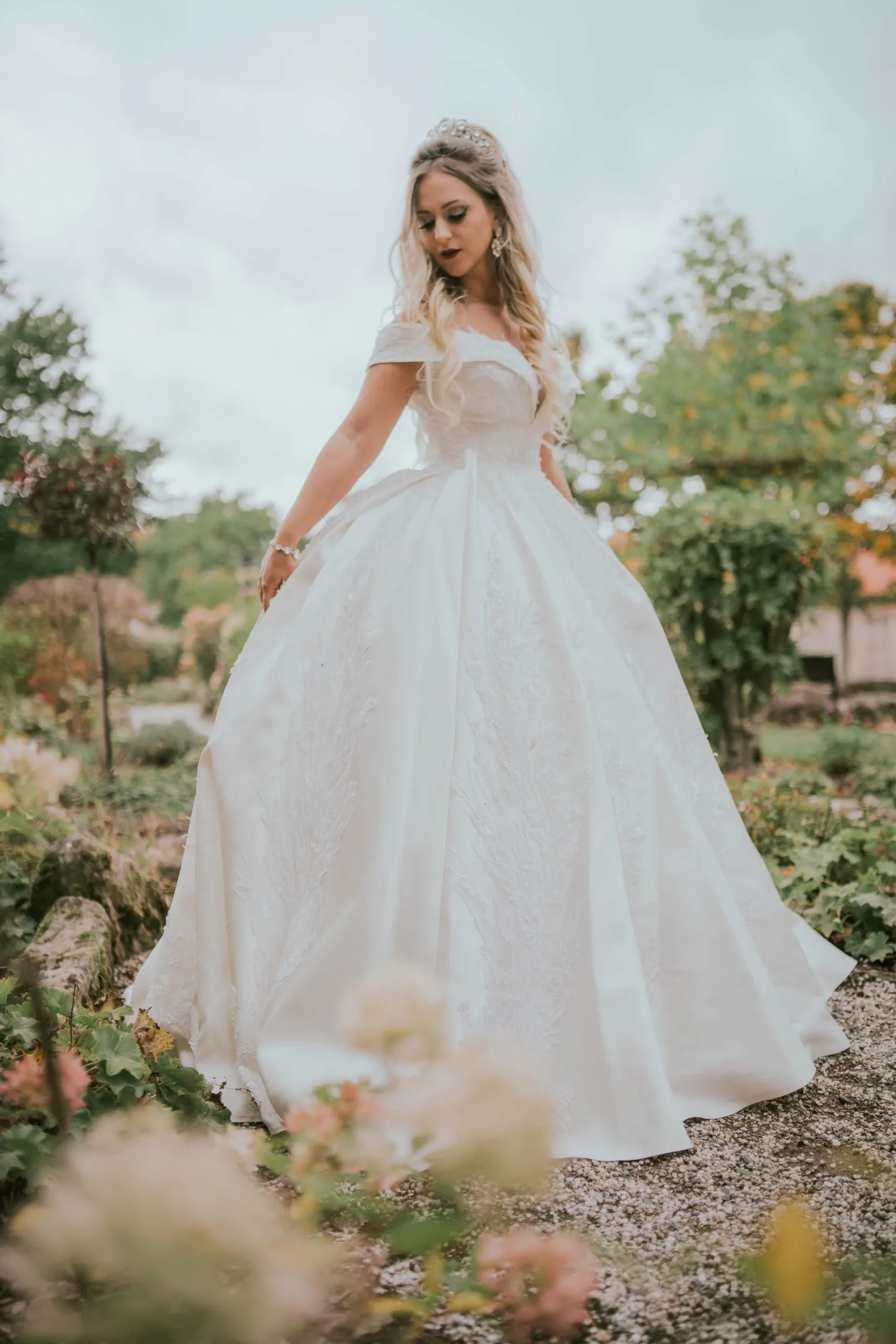 Braut im Ballkleid zwischen Blumen in einem Garten