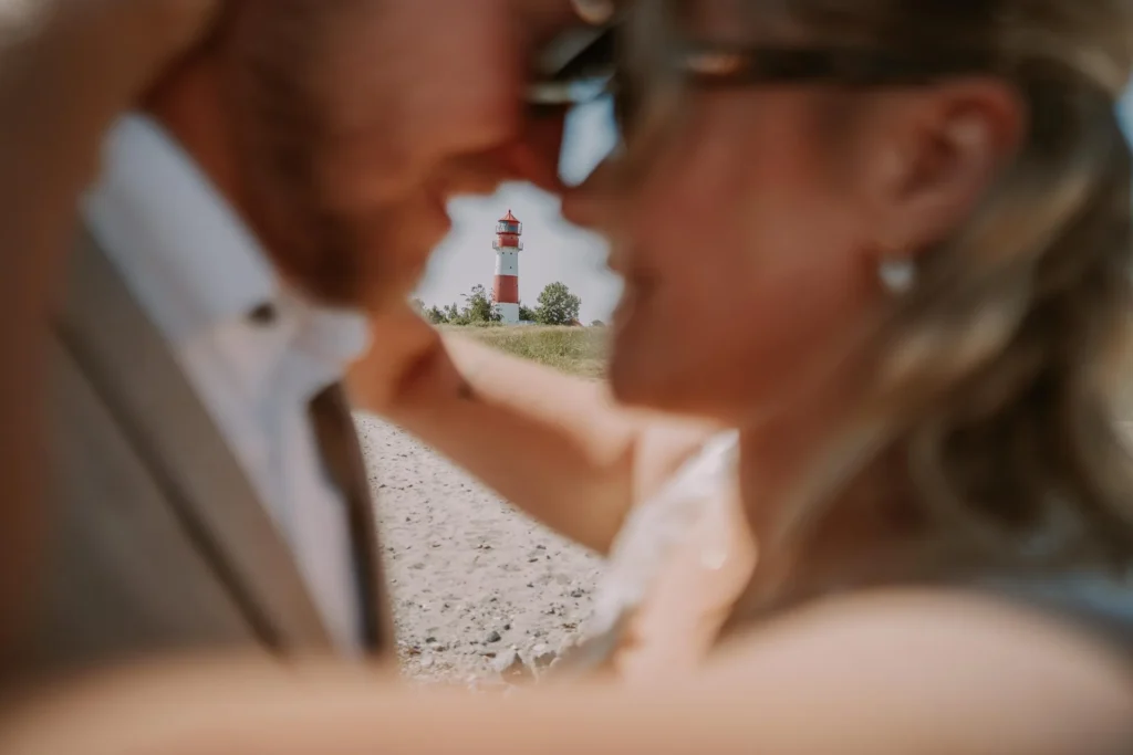Nahaufnahme: Brautpaar mit Sonnenbrille küsst sich an der Ostsee
