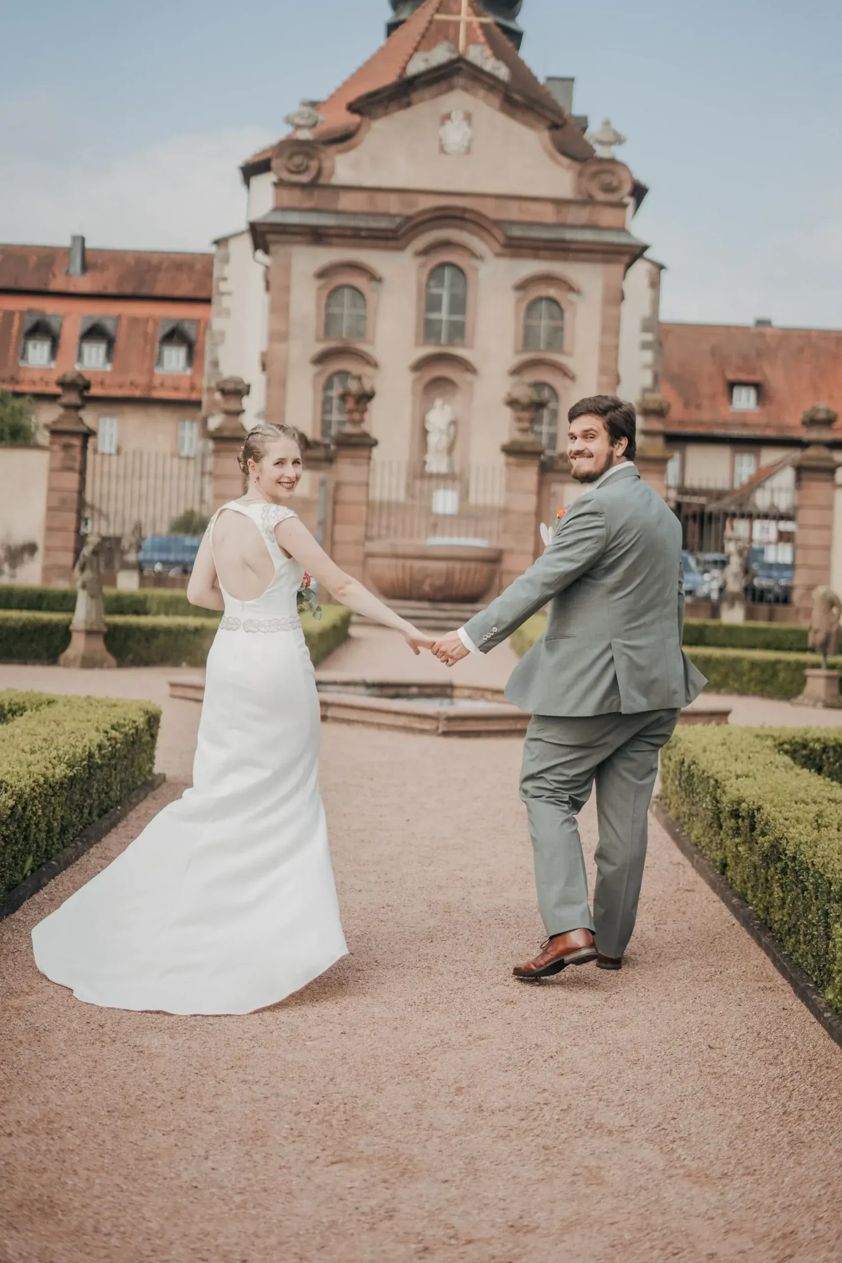 Brautpaar geht Hand in Hand auf dem Weg vor Schloss Fasanerie bei Fulda