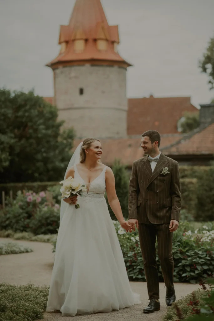 Brautpaar in einem Garten vor einem mittelalterlichen Turm im Schlossgarten Fulda