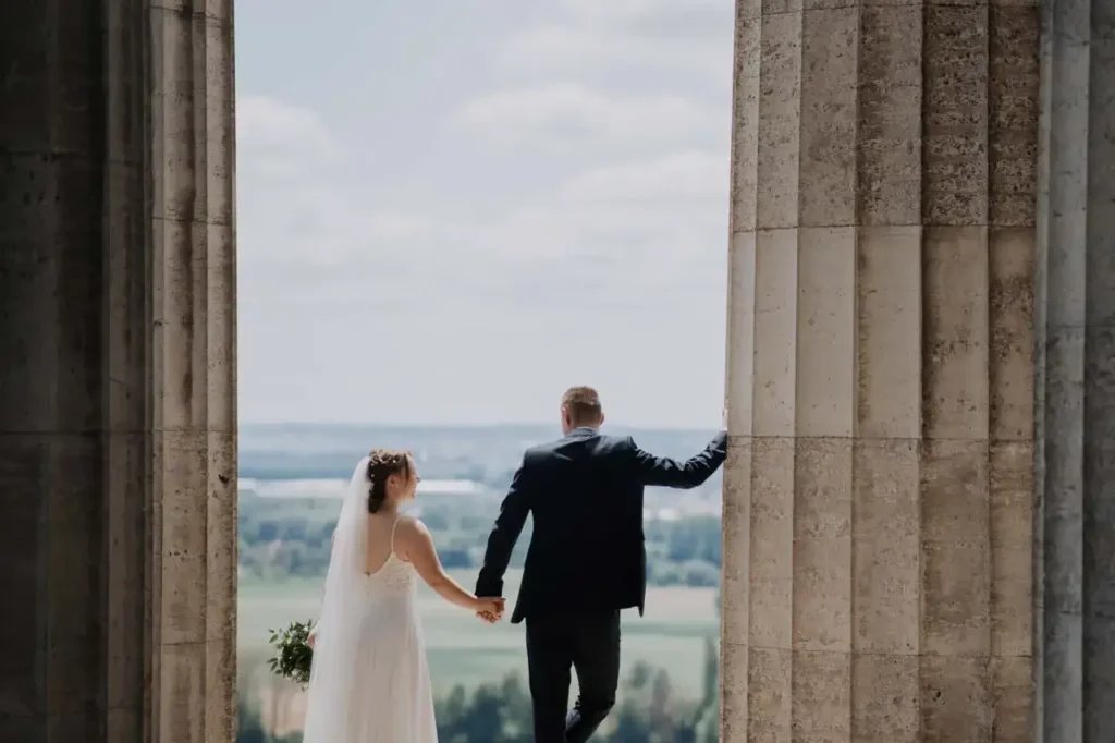 Hochzeit in Regensburg: Brautpaar zwischen den Säulen der Walhalla mit Blick über das Donautal