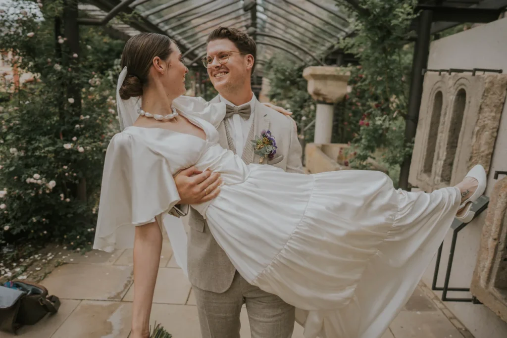 Konstantin hebt Gwen unter einer Pergola hoch