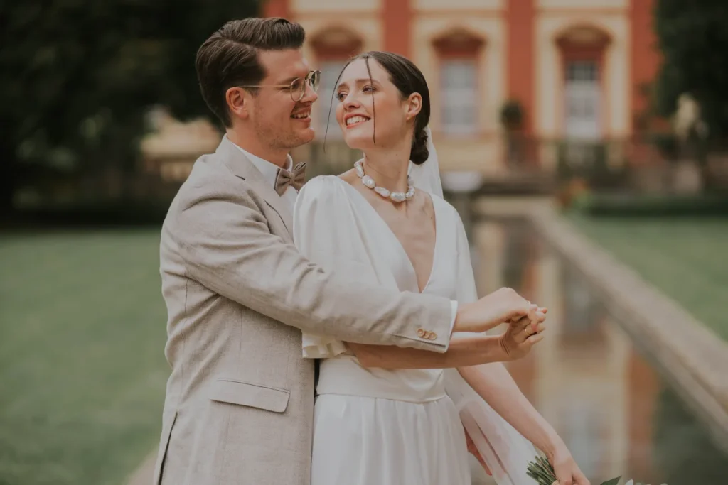Gwen und Konstantin umarmen sich vor einer roten Barockfassade