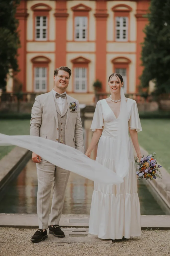 Gwen und Konstantin umarmen sich vor einer roten Barockfassade