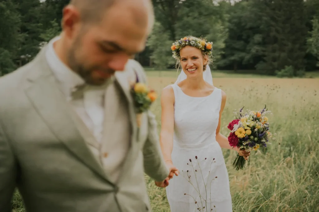 Brautpaar mit Blumenkranz und Brautstrauß auf einer Sommerwiese am Schloss Fasanerie bei Fulda