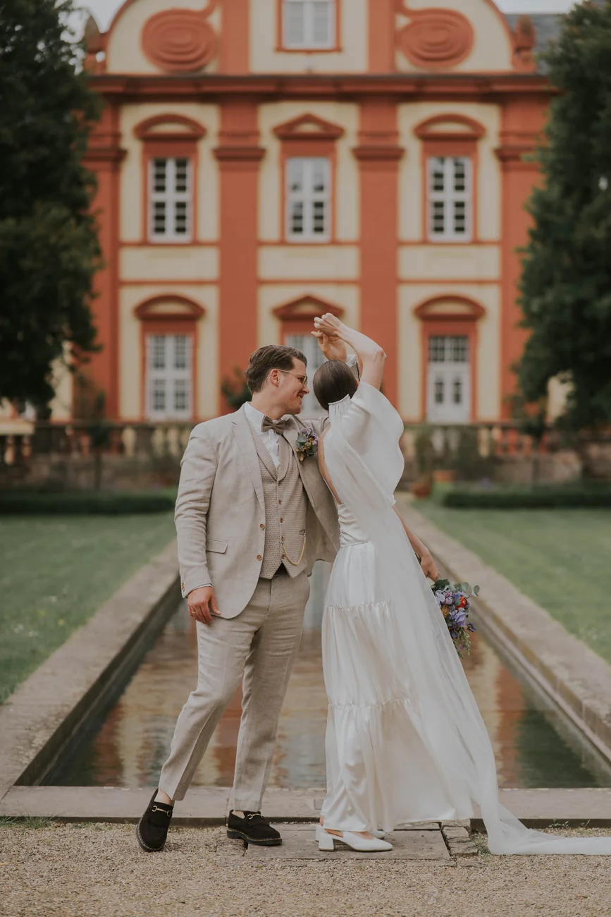 Brautpaar steht am Wasserbecken vor einem Barockbau im Dechaneigarten am Dom in Fulda